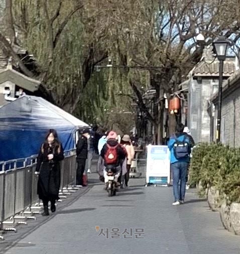 지난 3일 베이징의 유명 후퉁(전통골목)인 난뤄구샹 입구에서 주민들이 핵산 검사 결과를 제시하지 않고도 자유롭게 드나들고 있다. 베이징 류지영 특파원