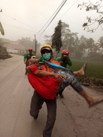 A rescuer evacuates an elderly resident following the eruption of Mount Semeru volcano in Lumajang, East Java province, Indonesia, December 4, 2022. Antara Foto/National Disasters Mitigation Agency (BNPB)/ via REUTERS  ATTENTION EDITORS - THIS IMAGE HAS BEEN SUPPLIED BY A THIRD PARTY. MANDATORY CREDIT. INDONESIA OUT. NO COMMERCIAL OR EDITORIAL SALES IN INDONESIA./2022-12-04 19:41:47/ <연합뉴스>