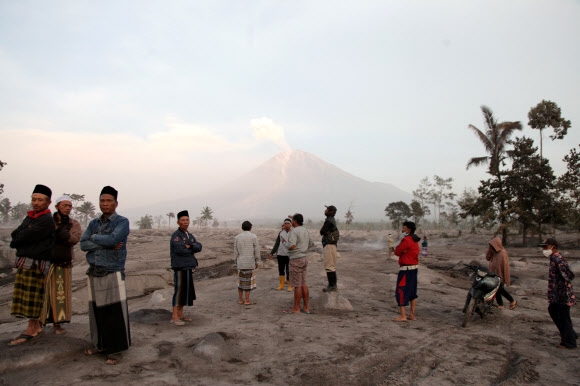 Villagers stand in an area covered with volcanic ash as Mount Semeru volcano erupts volcanic materials, as seen in the background in Sumberwuluh, Lumajang, East Java province, Indonesia, December 5, 2022, in this photo taken by Antara Foto. Antara Foto/Umarul Faruq/via REUTERS ATTENTION EDITORS - THIS IMAGE HAS BEEN SUPPLIED BY A THIRD PARTY. MANDATORY CREDIT. INDONESIA OUT. NO COMMERCIAL OR EDITORIAL SALES IN INDONESIA./2022-12-05 11:58:52/ <연합뉴스>