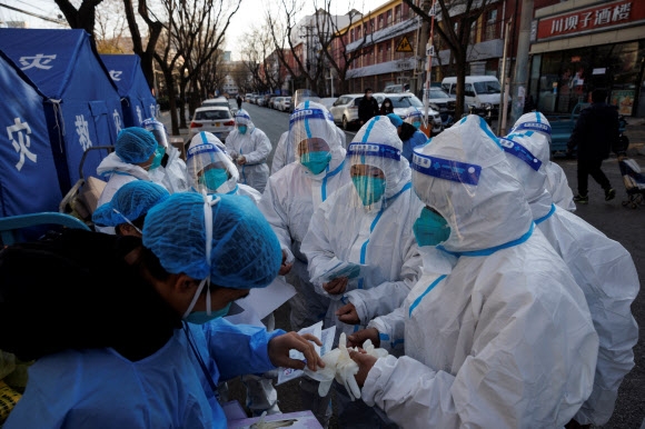 8일 중국 베이징에서 코로나19 감염자가 지속적으로 발생하는 가운데 방역요원들이 입주민이 자가격리 중인 건물을 둘러보는 근무를 시작하기 전 새 보호장비를 지급받고 있다. 베이징 로이터 연합뉴스