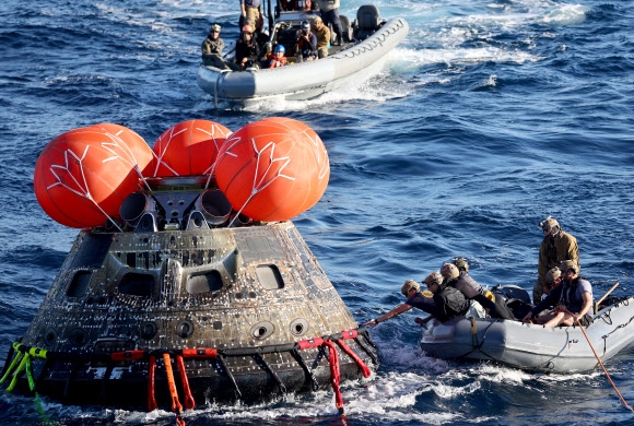 미 해군 잠수부들이 11일 멕시코 근처 태평양에서 나사가 발사한 무인우주선 오리온을 건져내고 있다. 연합뉴스
