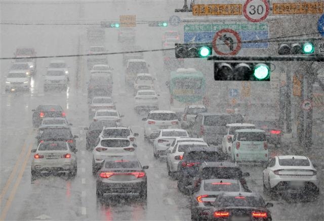 수도권 지역에 많은 눈이 내린 13일 오후 경기 수원시의 한 도로에서 차량들이 서행하고 있다. 뉴스1