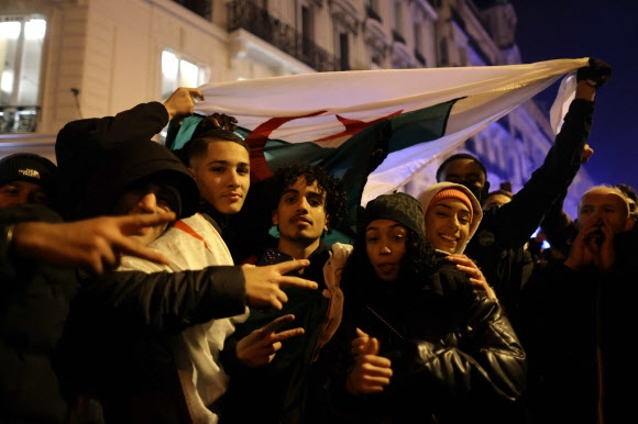 알제리 축구 팬들이 15일(한국시간) 파리 샹젤리제 거리에서 2022 카타르월드컵 프랑스와 모로코의 준결승을 화상으로 지켜본 뒤 자국 국기를 펼쳐 보이고 있다. 이들이 어느 쪽을 응원했는지 여부는 통신이 밝히지 않았다. 파리 AFP 연합뉴스 
