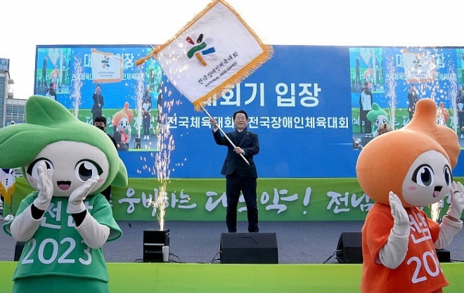 김영록 전라남도지사가 15일 오후 목포역 광장에서 열린 ‘2023년 제104회 전국체육대회·제43회 전국장애인체육대회’ 의 사전 붐 조성과 성공개최를 다짐하는 D-300일 기념행사에서 체육회 대표선수로 부터 양(兩) 대회기를 전달받아 흔들고 있다. 