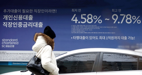 지난 15일 한 시민이 서울 시내 한 시중은행에 걸린 대출 금리 안내문 앞을 지나고 있다. 연합뉴스