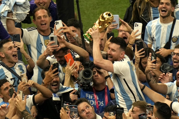 아르헨티나의 리오넬 메시가 19일 카타르 루사일 스타디움에서 열린 프랑스와의 월드컵 결승전에서 아르헨티나가 승리한 후 팬들과 함께 우승 트로피를 들고 축하하고 있다. 2022.12.19 AP연합뉴스