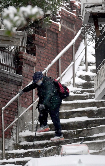 전국 곳곳에 대설주의보가 내려진 21일 서울 서대문구 북아현동에서 한 시민이 지팡이를 짚으며 눈이 쌓인 가파른 계단을 내려오고 있다. 이날 수도권을 중심으로 많은 눈이 내리며 출근길 혼란이 빚어졌다. 홍윤기 기자