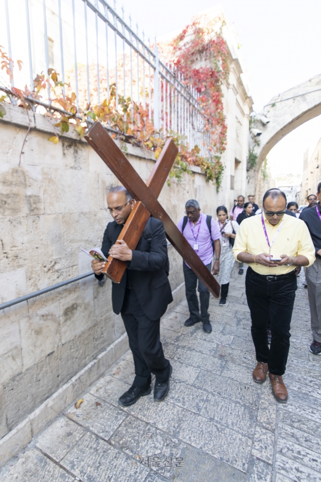 이스라엘 예루살렘 ‘비아 돌로로사’를 찾은 이들이 예수처럼 십자가를 지고 걷는 순례객의 뒤를 따르고 있다.