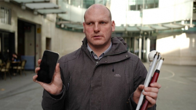 휴대전화를 빼앗아 달아나려던 범민들에게 본능적으로 몸을 날려 기어이 되찾은 영국 BBC의 시각장애인 기자 숀 딜리가 되찾은 전화를 들어 보이고 있다. BBC 홈페이지 캡처