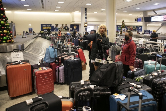 27일(현지시간) 미국 시카고 공항에서 분실된 짐들 사이에서 자신의 것을 찾으려 하고 있다. AP