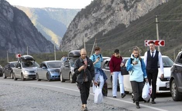 러시아와 조지아간 국경 지역인 베르흐니 라르스에서 28일 국경을 넘으려는 차량들이 긴 줄을 서 있는 가운데 일부 러시아인들이 도보로 국경검문소로 향하고 있다. 2022.9.28  AP 연합뉴스