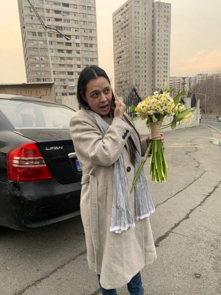이란 여배우 타라네흐 알리두스티가 4일(현지시간) 수도 테헤란의 에빈 교도소에서 풀려난 뒤 환영하러 나온 친구들로부터 받은 꽃 부케를 든 채 누군가와 통화하고 있다. 일간 샤르그 제공 AP 연합뉴스 