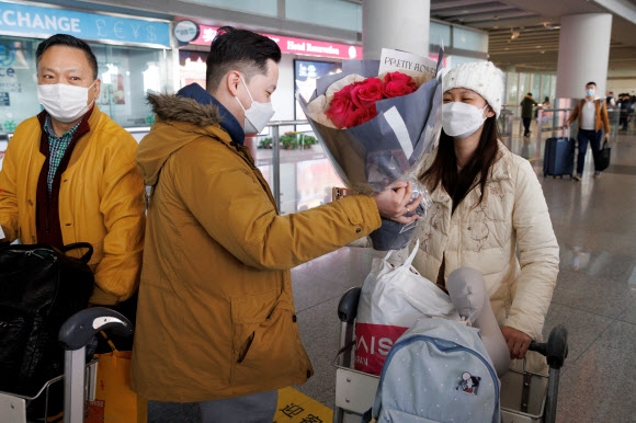 중국에서 공식적으로 입국 격리가 해제된 8일 베이징 서우두 국제공항에서 한 남성이 해외에서 들어 온 여성에게 꽃다발을 주며 입국을 축하하고 있다. 베이징 로이터 연합뉴스