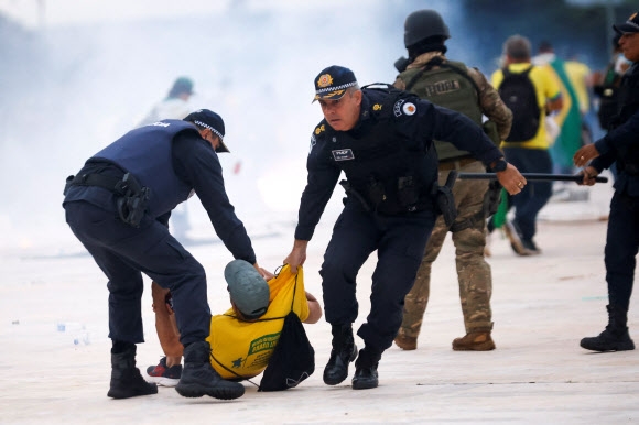 브라질 보안군이 8일 브라질 브라질리아에서 열린 루이스 이나시오 룰라 다 실바 대통령에 반대하는 시위 도중 자이르 보우소나루 전 브라질 대통령의 지지자를 끌고 가고 있다. 로이터 연합뉴스