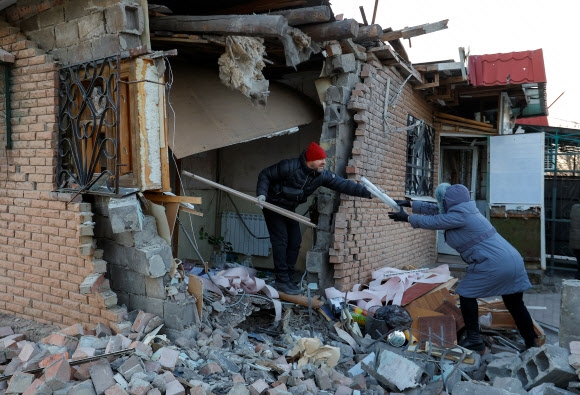 우크라이나 도네츠크 지역 주민들이 폭격으로 무너진 집을 치우고 있다. 로이터 연합뉴스