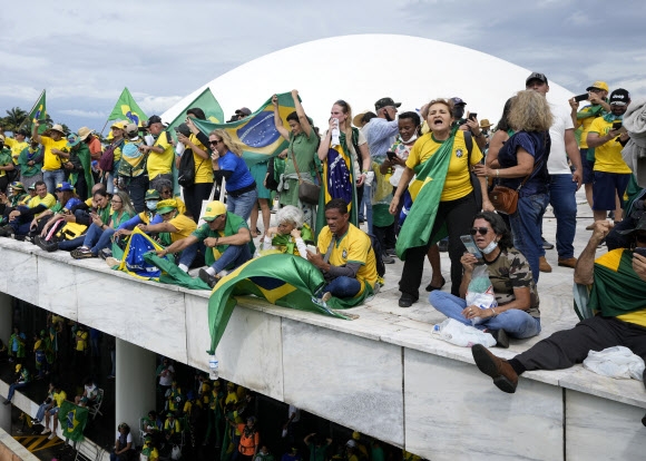 Apoiadores do ex-presidente Jair Bolsonaro sobem no telhado da Assembleia Nacional em Brasília, Brasil, no dia 8 (horário local).  AP Yonhap News
