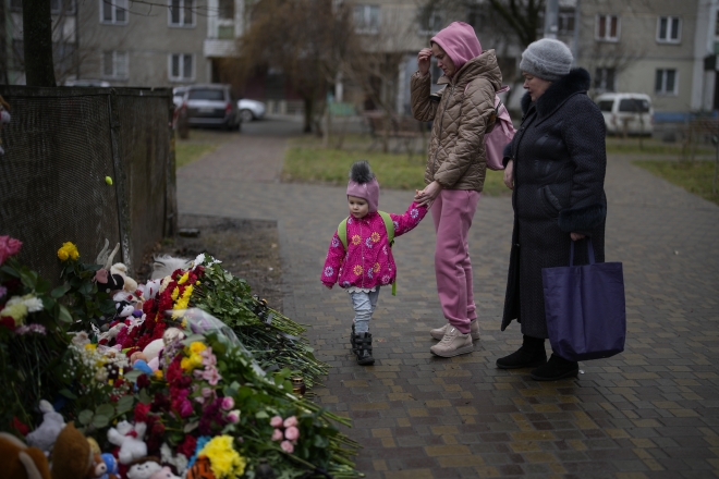 아이의 손을 잡은 우크라이나 키이우 외곽 브로바리 지역 시민들이 20일(현지시간) 추모의 꽃이 놓인 헬리콥터 추락 사고 지점을 지나고 있다.  브로바리 AP 연합뉴스