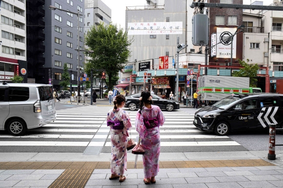 4일 일본 도쿄의 번화가 아사쿠사 거리에서 여성 2명이 일본 전통의상을 입고 횡단보도 신호를 기다리고 있다. 도쿄 AFP 연합뉴스