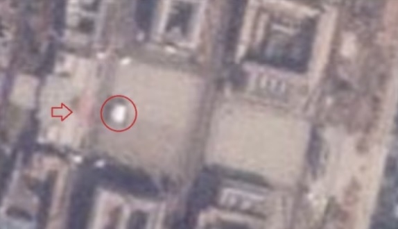 민간 위성 사진 업체 ‘플래닛 랩스’가 북한 김일성 광장을 촬영한 4일자 위성사진. 김일성 광장 연단(화살표)에 붉은색 인파가 몰려있다. 광장 중심부에는 하얀색 구조물(원 안)이 설치됐다. 미국의 소리(VOA) 홈페이지 캡쳐