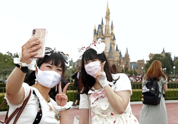 일본 도쿄 인근의 디즈니랜드를 찾은 일본인들이 마스크를 쓴 채 사진을 찍고 있다. AP 연합뉴스