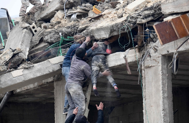 튀르키예에서 규모 7.8과 7.5의 강진이 잇따라 발생한 6일(현지시간) 인접한 시리아 알레포주 아프린시 잔다리스의 붕괴한 건물 잔해에서 시민들이 다친 여자아이를 구조하고 있다. 아프린시는 시리아 반군이 장악한 곳이다. 연합뉴스