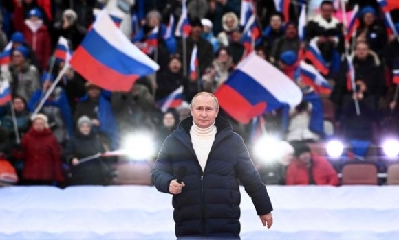 블라디미르 푸틴 러시아 대통령이 18일(현지시간) 모스크바 루즈니키 경기장에서 열린 크림반도 병합 8주년 기념 콘서트 연단에 오르고 있다. 무대 뒤로 ‘러시아를 위하여’, ‘나치즘 없는 세상을 위하여’ 등 문구가 보인다. 2022.3.18 AFP 연합뉴