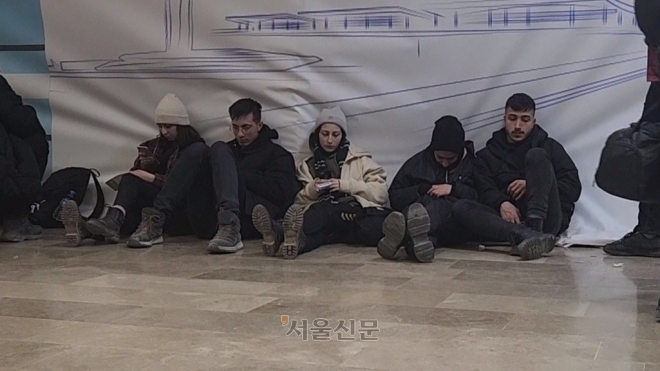 항공권을 미처 예매하지 못한 이재민들이 15일(현지시간) 튀르키예 아다나 공항에서 취소 표가 나오기를 기다리며 공항 한편에 앉아 있다.