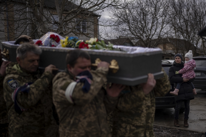 A man holding a girl watches as the funeral procession with the body of Kostiantyn, 35, passes by during his funeral in Borova, near Kyiv, Ukraine, Saturday, Feb. 18, 2023. Kostiantyn Kostiuk, a civilian who was a volunteer in the armed forces of Ukraine, was wounded during a battle against Russians on Jan. 23rd near Bakhmut and finally died on Feb. 10th in a hospital. (AP )