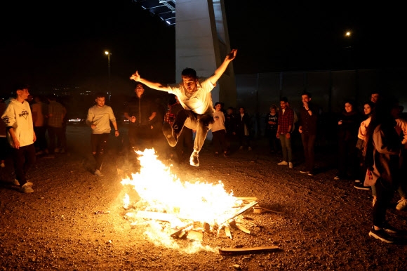 이란 테헤란에서 14일 밤(현지시간) ‘차하르 샴베 수리’를 축하하기 위해 한 남성이 모닥불 위에서 점프를 하고 있다. AFP연합뉴스