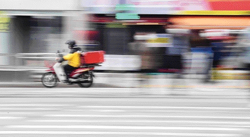 서울 강남구 논현역 인근 횡단보도에서 한 배달 오토바이가 보행자 신호에 횡단보도를 건너는 사람들 사이를 지나가며 신호를 위반하고 있다.