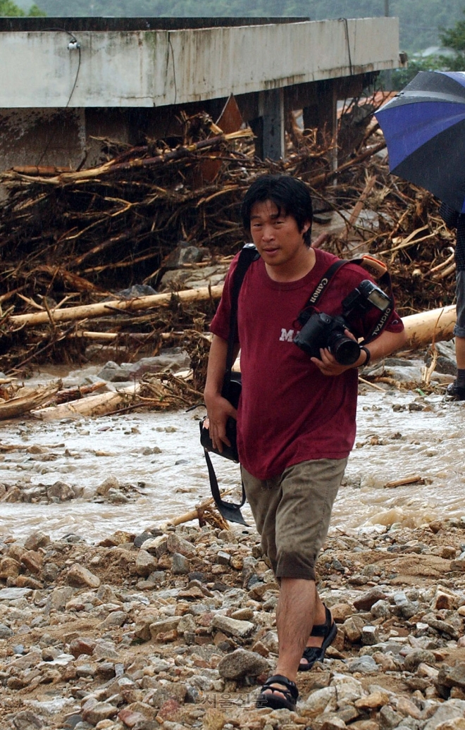 수해로 흔적이 사라지고 있는 마을에서 취재를 하고 있는 사진기자.