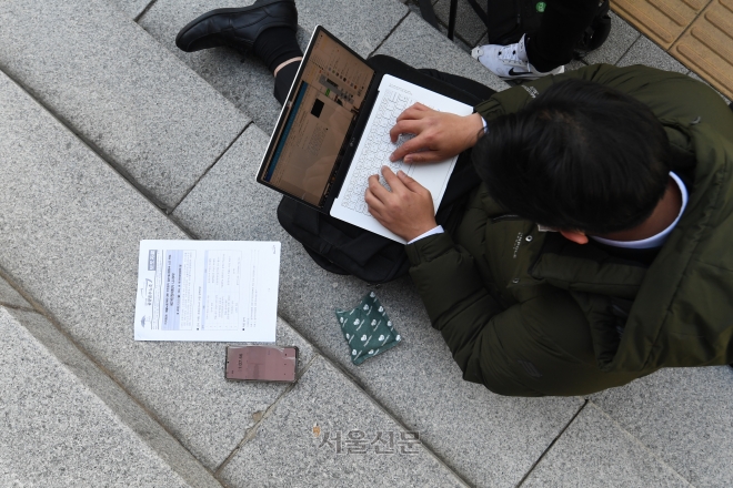지난해 12월 5일 서울 중구 국가인권위원회 앞에서 화물노동자에 대한 업무개시명령과 관련한 기자회견을 취재하는 한 기자. 핫팩으로 짐작할 수 있는 추운 날씨에도 바닥에 앉아 타이핑을 하고 있다.
