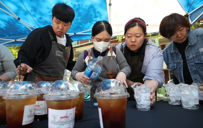 장애인의 날을 하루 앞둔 19일 오후 서울 용산구 용산가족공원 장교숙소 일대에서 장애인의 날 기념 행사가 열린 가운데 장애인과 비장애인 바리스타가 함께 시민들에게 커피를 나눠주고 있다. 뉴스1