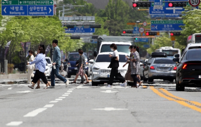 시민들이 일찍 찾아온 더위로 아지랑이가 피어오르는 도로를 건너고 있다.  광주 연합뉴스