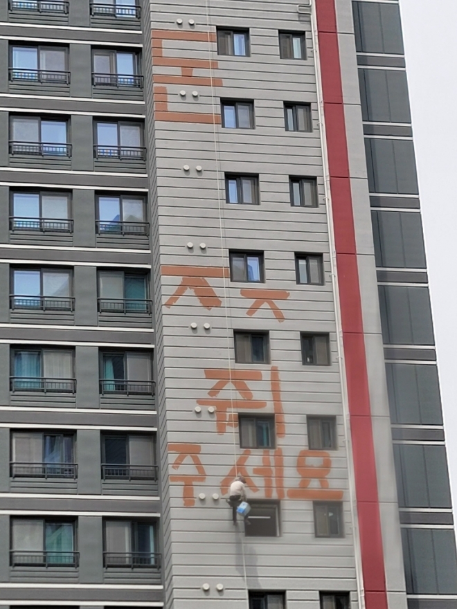 화성시 반월동의 아파트 신축 현장에서 한 작업자가 밀린 임금을 달라며  붉은색 페인트로 “돈 주세요”라는 글씨를 쓰며 고공 농성을 벌이고 있다. 경기소방재난본부 제공