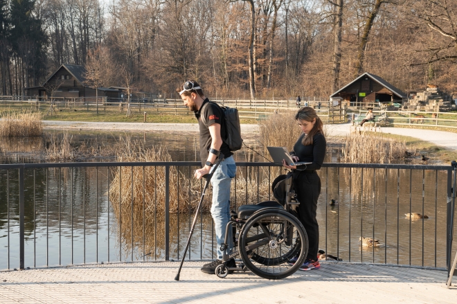 ‘디지털 브리지’ 장치를 장착한 환자가 과학자와 함께 걷는 실험을 하는 모습. 전신마비 환자가 디지털 브리지 장치를 통해 목발을 짚고 걷거나 혼자 휠체어를 움직일 수 있게 됐다.  스위스 로잔대병원 제공