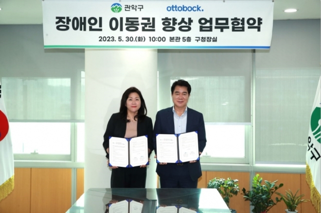 박준희(오른쪽) 서울 관악구청장이 재활 의료기기 기업인 오토복코리아헬스케어와 장애인 이동권 향상을 위한 업무협약을 맺고 기념사진을 촬영하고 있다. 관악구 제공