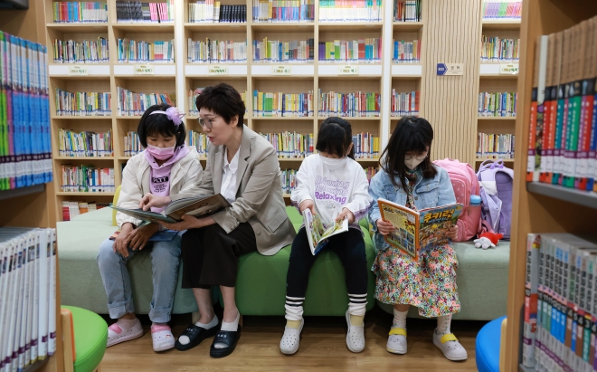 대전 중구 보성초등학교에서 늘봄 전담사 이은순 씨(왼쪽 두 번째)가 일찍 등교한 학생들과 책을 읽고 있다.  연합뉴스