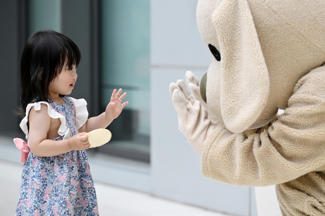 1일 오후 서울 김포공항 국내선 청사에서 열린 애견센터 개소식장 앞을 지나는 한 어린이가 강아지 마스코트에게 인사하고 있다. 2023.6.1. 도준석 기자