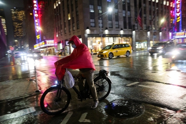 한 배달 노동자가 23일(현지시간) 미국 뉴욕시 맨해튼 시내에서 우비를 뒤집어 쓰고 배달을 하고 있다. 로이터 연합뉴스