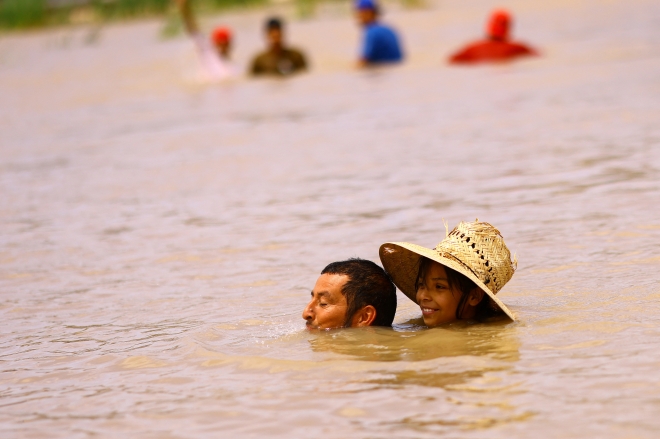 18일(현지시간) 미국과 국경을 맞댄 멕시코 시우다 후아레스 지역의 리오 브라보 강에서 사람들이 강물에 뛰어들어 더위를 식히고 있다. 로이터 연합뉴스