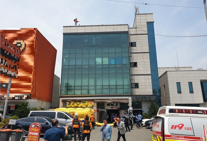 19일 오전 충남 천안의 한 4층 건물 옥상 난간에서 50대 여성이 자신의 근로계약과 관련해  부당한 해고를 주장하고 있다. 독자 제공