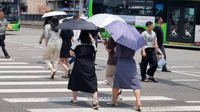 이틀째 폭염주의보가 발효된 19일 오전 서울 종로구 적선동에서 시민들이 양산을 쓰고 횡단보도를 건너고 있다. 김예슬 기자