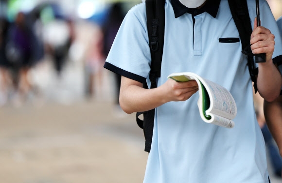 21일 서울 강남구 대치동 학원가에서 한 학생이 걸어가면서 책을 보고 있다. 연합뉴스
