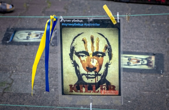 블라디미르 푸틴 러시아 대통령에 희생된 이들을 추모하는 집회가 열린 24일(현지시간) 독일 프랑크푸르트에서 그의 초상을 훼손한 포스터가 눈에 띈다. 프랑크푸르트 AP 연합뉴스