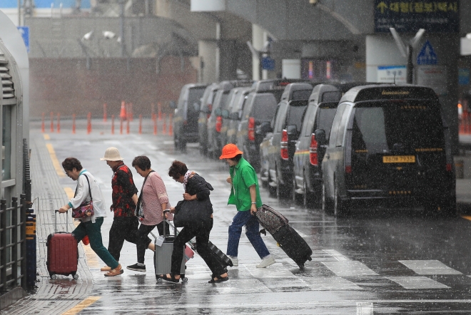 올해 첫 장맛비가 시작된 25일 제주국제공항에서 우산을 챙기지 못한 관광객들이 비를 맞으며 횡단보도를 빠르게 건너가고 있다. 제주 뉴시스