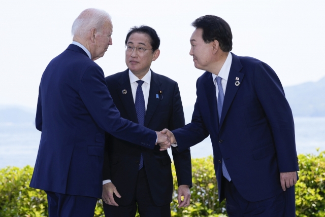 윤석열 대통령(오른쪽)과 조 바이든 미국 대통령(왼쪽)이 5월 21일 일본 히로시마에서 주요 7개국(G7) 정상회의를 계기로 열린 한미일 정상회담을 앞두고 기시다 후미오 일본 총리가 지켜보는 가운데 악수하고 있다. 연합뉴스