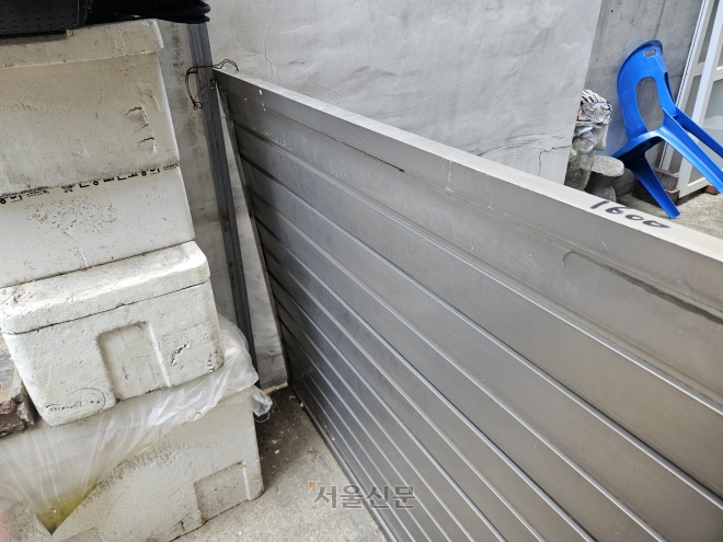 26일 대림동의 한 반지하 주택 입구에 설치된 차수판이 철사 고리로 느슨하게 연결돼 있다. 강동용 기자