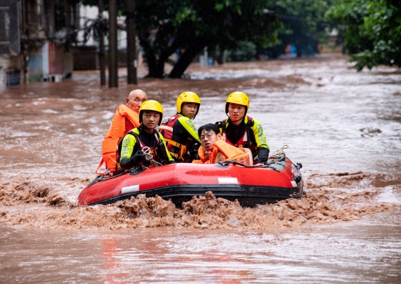 중국 구조요원들이 4일 충칭 시의 완저우 지구에 폭우가 쏟아져 물난리가 덮치자 오도가도 못한 주민들을 구조하고 있다. 충칭 로이터 연합뉴스