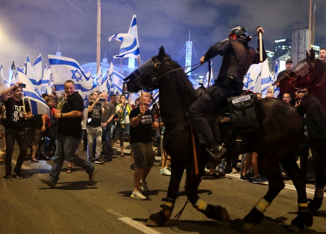 5일(현지시간) 이스라엘 텔아비브 경찰청장 사임 직후 한 시위자가 곤봉을 든 기마 경찰과 마주하고 있다.  텔아비브 로이터 연합뉴스